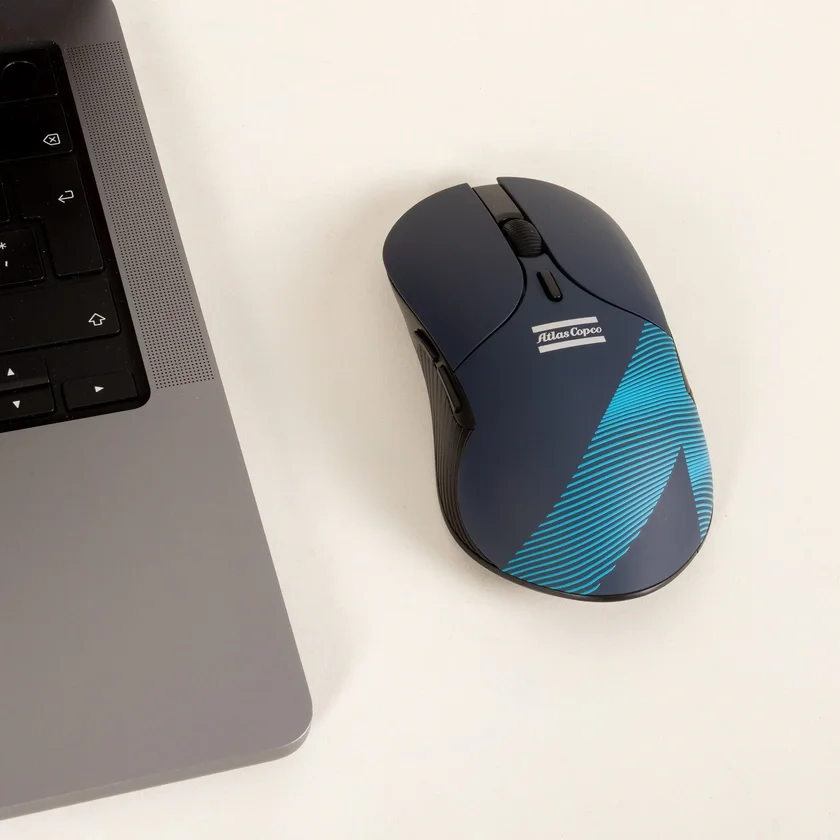 Blue mouse with atlas copco logo and wave pattern next to a laptop